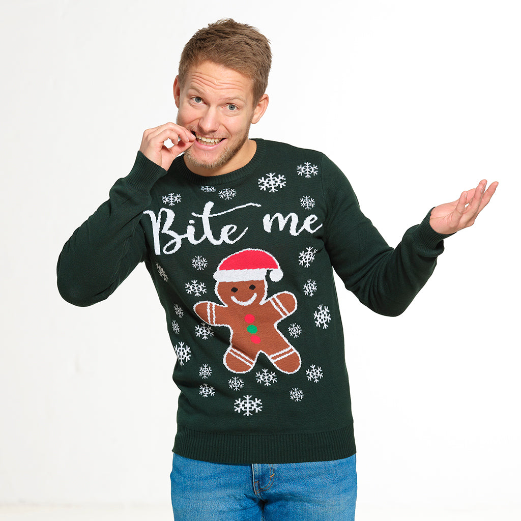 En man poserar i en grön jultröja med en kaka och citatet